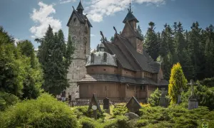 Drewniany kościółek i kamienna wieża z zegarem, otoczone zielenią i nagrobkami. Jedna z głównych karpacz atrakcji.