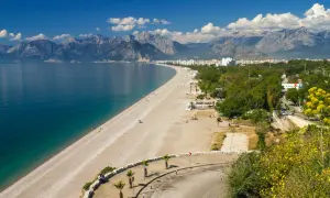 Piękna plaża i turkusowe morze w Turcji, idealne miejsce na wakacje. W tle góry i miasto.