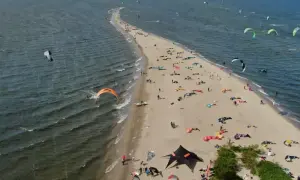 Rewa atrakcje dla dzieci: plaża pełna kolorowych latawców do kitesurfingu i ludzi odpoczywających na piasku.