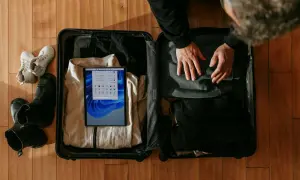 Pakowanie walizki: buty, ubrania i tablet z listą "co zabrać do Londynu".