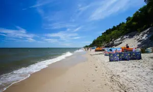 Słoneczna plaża w Chłapowie z kolorowymi parawanami, idealna na rodzinne wakacje. Atrakcje dla dzieci czekają!