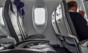 Wnętrze samolotu Boeing 737-800. Widok na rzędy czarnych, skórzanych siedzeń i okna. Jeden z pasażerów siedzi przy oknie.