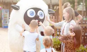 Dzieci dotykają wielkiej, pluszowej owcy. To fajne miejsce na weekend z dzieckiem, pełne radości i uśmiechów.