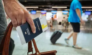 Ręka trzyma paszport i kartę pokładową, gotowa do podróży. Dowiedz się, jak tanio latać i odkrywać świat!