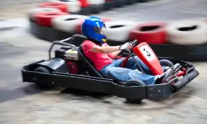 Dziecko w niebieskim kasku śmiga gokartem po torze w Warszawie. Emocjonująca jazda gokartami dla dzieci.