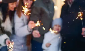 Rodzina z dziećmi świętuje Sylwestra, trzymając zimne ognie. Idealne miejsce, gdzie na sylwestra z dziećmi, by stworzyć magiczne wspomnienia.