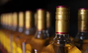 Rząd butelek z alkoholem, przypominający o limitach w Islandii. Złote zakrętki i bursztynowy płyn.