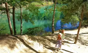 Dwie dziewczynki w słomkowych kapeluszach spacerują ścieżką nad turkusowym jeziorem. Idealne miejsce, gdzie w góry z dziećmi latem.