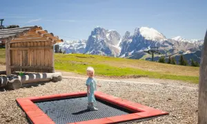 Mały chłopiec cieszy się zabawą na trampolinie na tle majestatycznych Dolomitów.