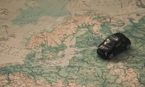 Czarny Fiat 500 na mapie Europy, sugerujący podróż do Włoch samochodem.