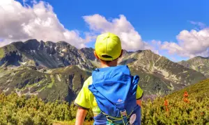 Chłopiec w żółtej czapce i niebieskim plecaku podziwia majestatyczne Tatry.