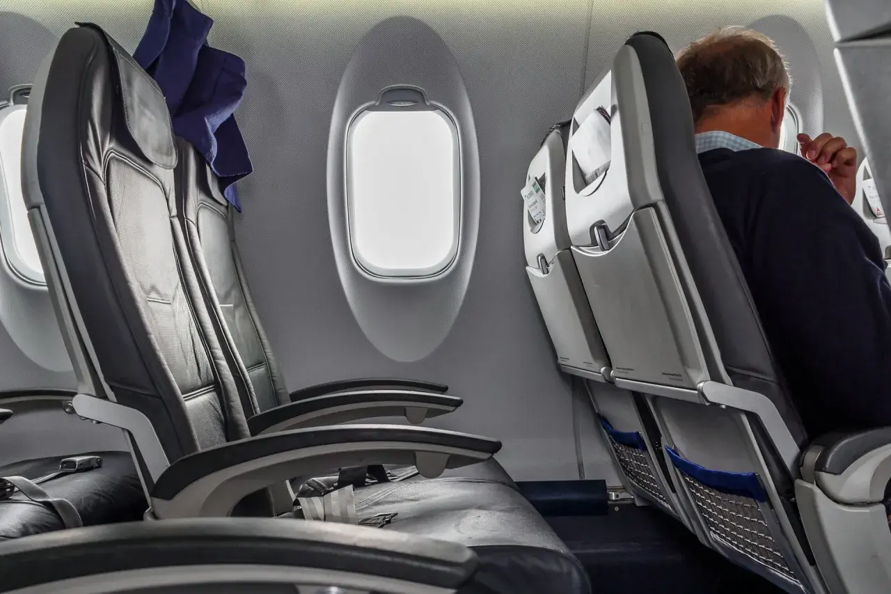 Wnętrze samolotu Boeing 737-800. Widok na rzędy czarnych, skórzanych siedzeń i okna. Jeden z pasażerów siedzi przy oknie.