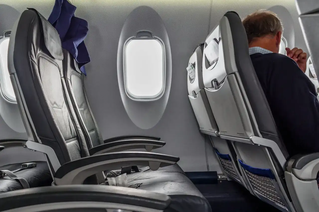 Wnętrze samolotu Boeing 737-800. Widok na rzędy czarnych, skórzanych siedzeń i okna. Jeden z pasażerów siedzi przy oknie.