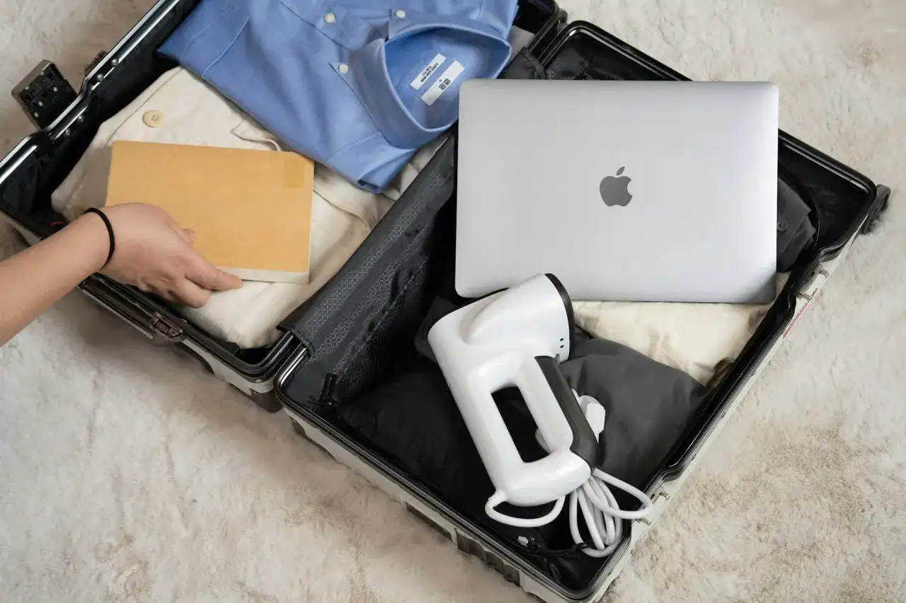 Pakowanie bagażu rejestrowanego: laptop, parownica do ubrań i książka. Elektronika w bagażu rejestrowanym to wygoda w podróży.