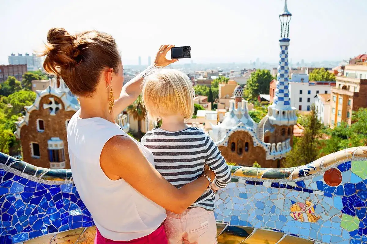 Mama z dzieckiem podziwiają kolorowe budowle Parku Güell, idealne atrakcje dla dzieci w Barcelonie.