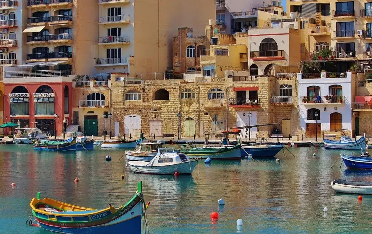 Malta: maltański port z kolorowymi łodziami i kamiennymi budynkami. Czy na Maltę potrzebny jest paszport? Tak, jeśli podróżujesz spoza strefy Schengen.