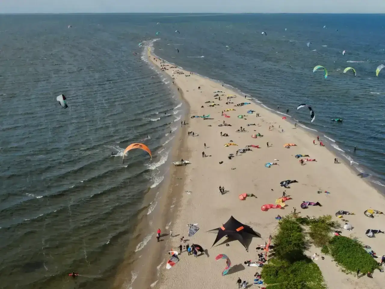 Rewa atrakcje dla dzieci: plaża pełna kolorowych latawców do kitesurfingu i ludzi odpoczywających na piasku.
