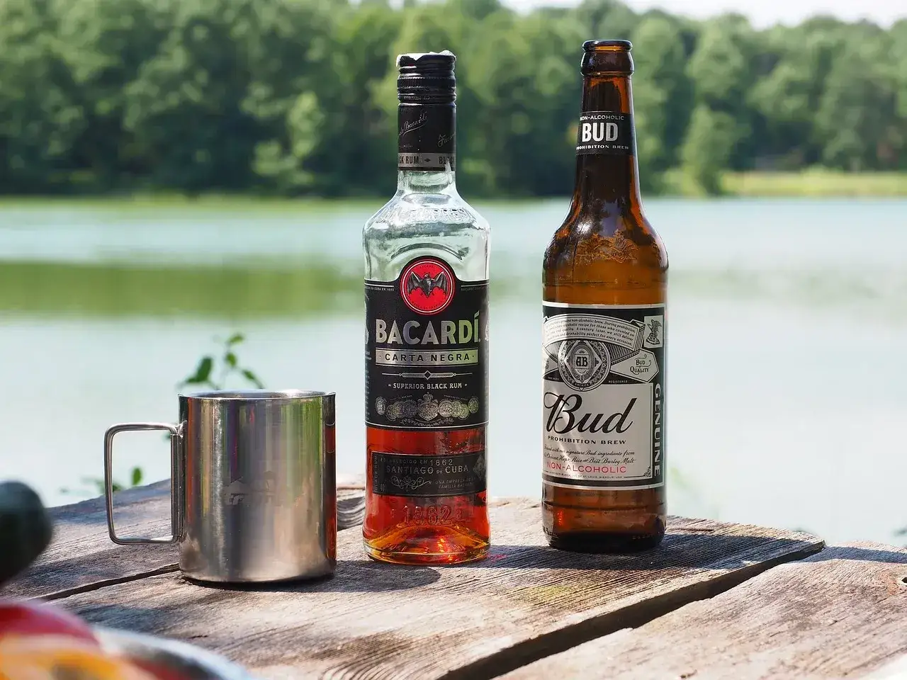 Islandia alkohol limit. Butelka Bacardi i piwo Bud na drewnianym stole nad jeziorem.