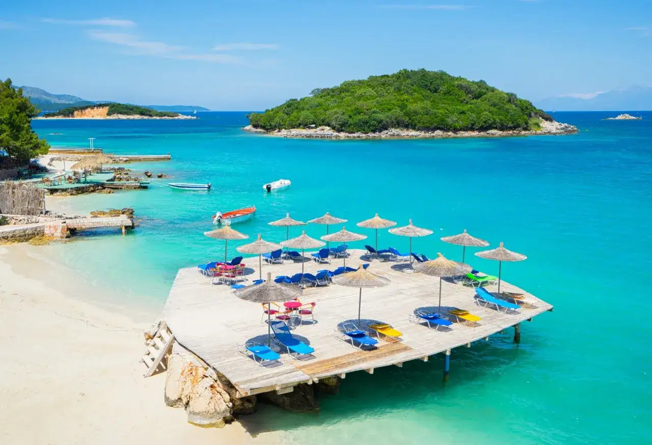 Albania z dziećmi: rajska plaża z turkusową wodą, leżakami i parasolami. Idealne miejsce na rodzinne wakacje.