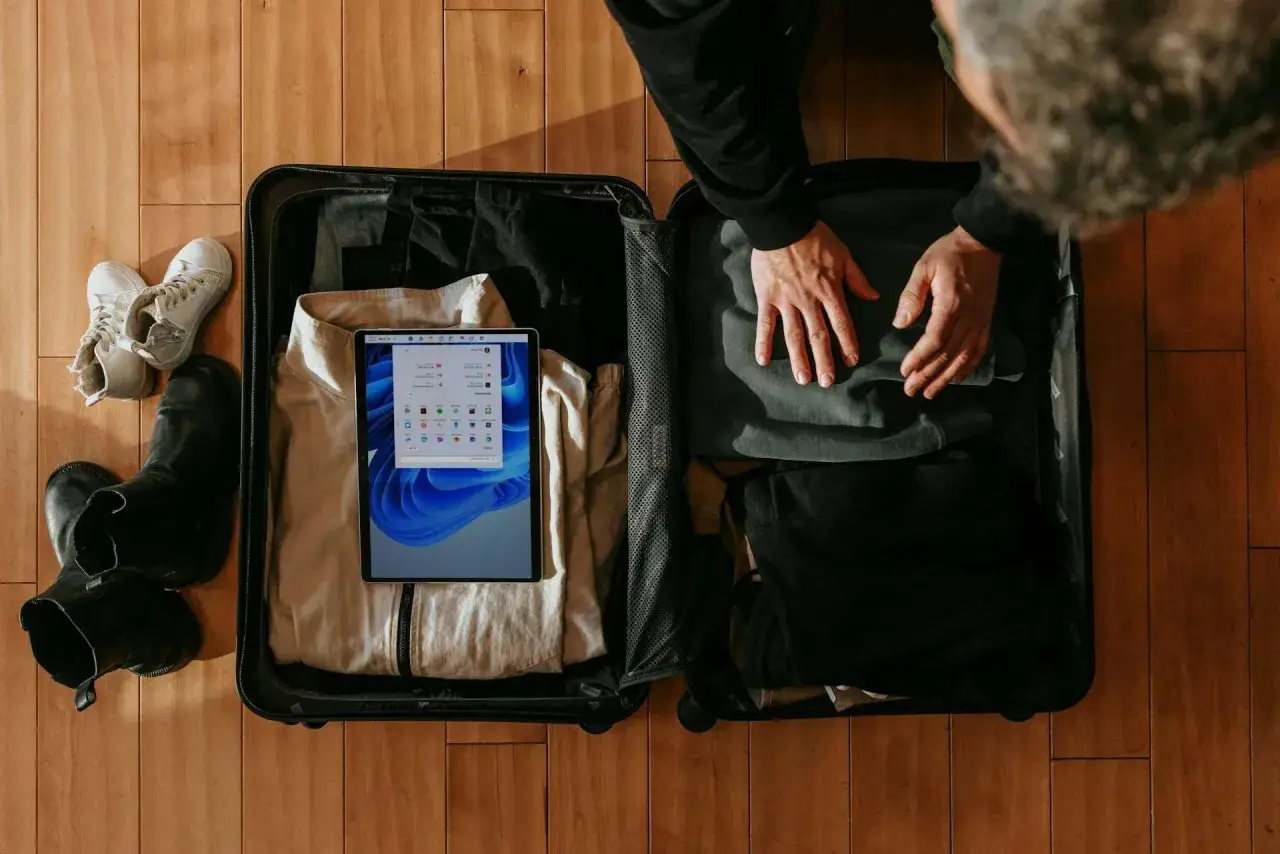 Pakowanie do walizki: buty, ubrania i tablet z widokiem na enter air bagaż.