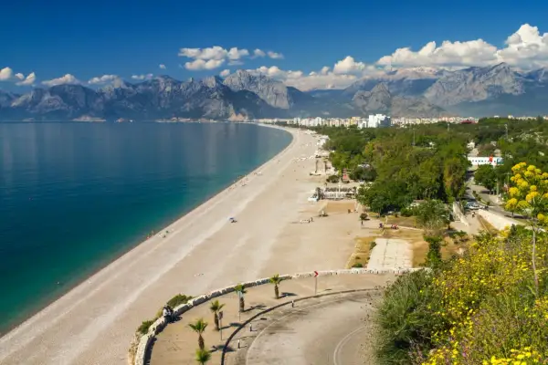 Piękna plaża i turkusowe morze w Turcji, idealne miejsce na wakacje. W tle góry i miasto.