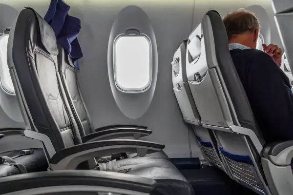Wnętrze samolotu Boeing 737-800. Widok na rzędy czarnych, skórzanych siedzeń i okna. Jeden z pasażerów siedzi przy oknie.